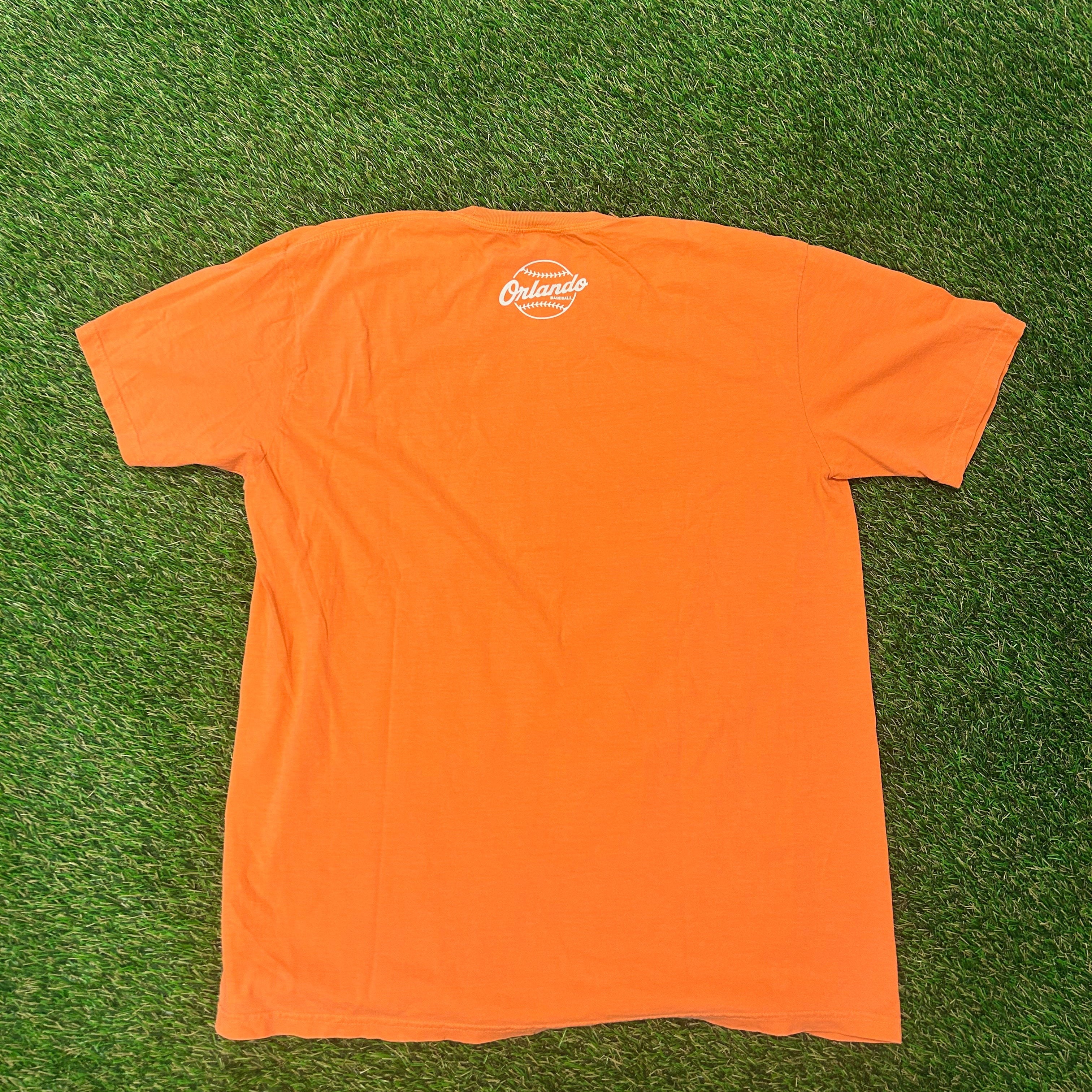 Orange t-shirt with a logo on a green grass background