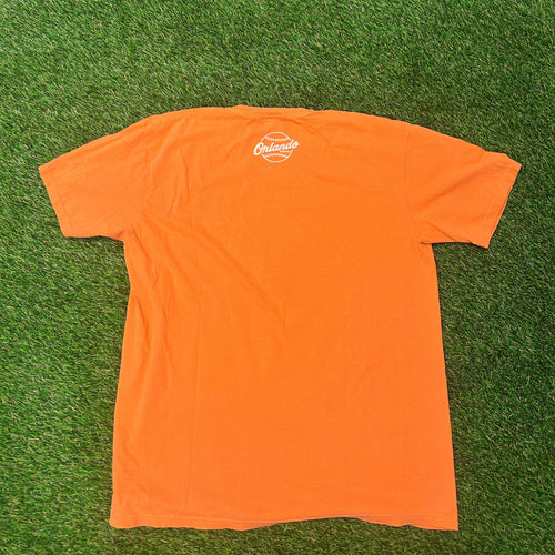 Orange t-shirt with a logo on a green grass background