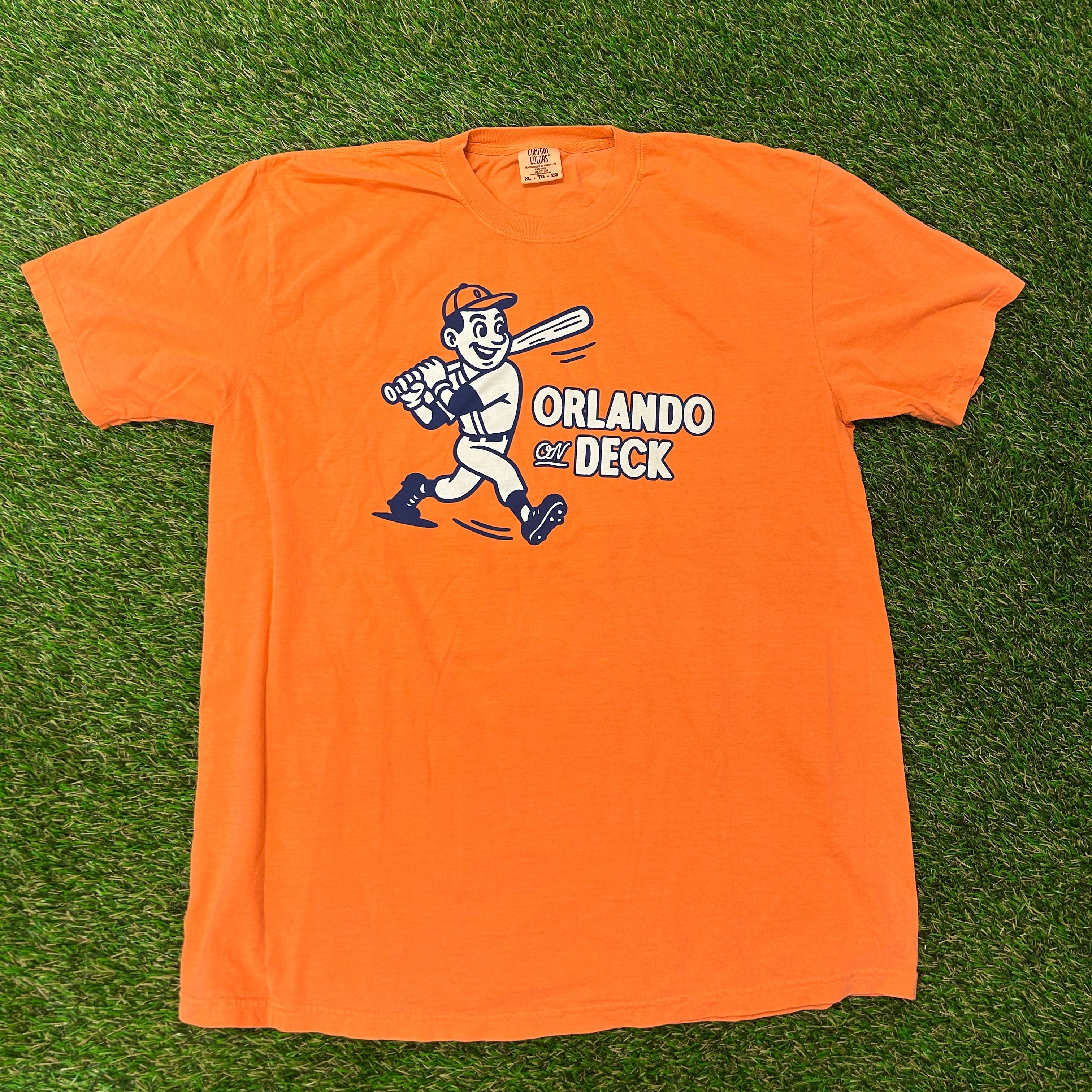 Orange long-sleeve shirt with a graphic design on a grassy background