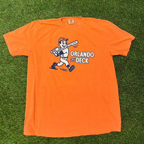 Orange long-sleeve shirt with a graphic design on a grassy background